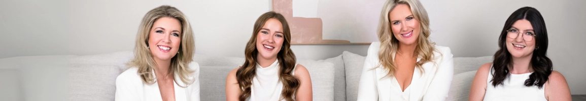 The Honest Talk's team dressed in white, sitting on a white couch and smiling to the camera