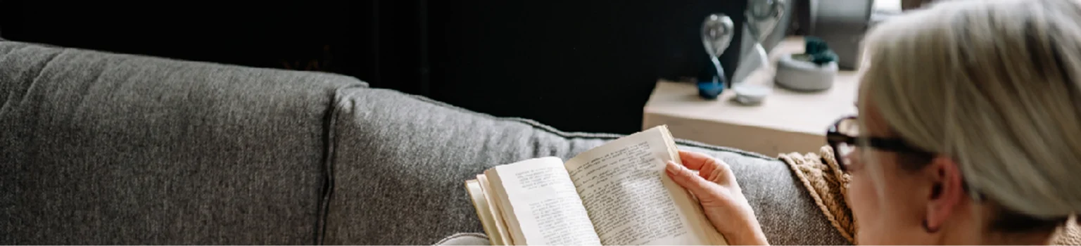 A woman reads a book on a sofa