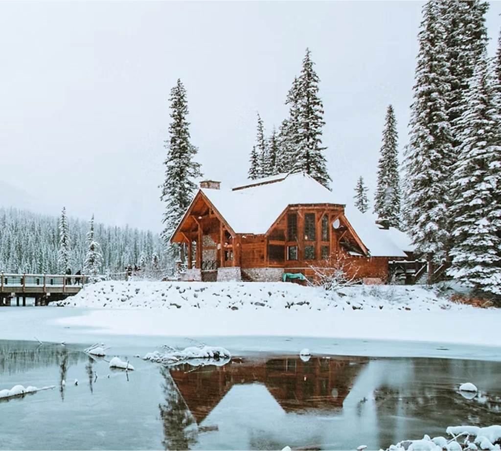 A large, nice cabin surrounded by snow and trees
